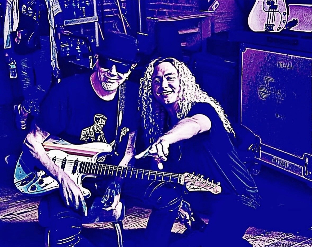 Mark Kendall and Brett Carlisle backstage with a white electric guitar