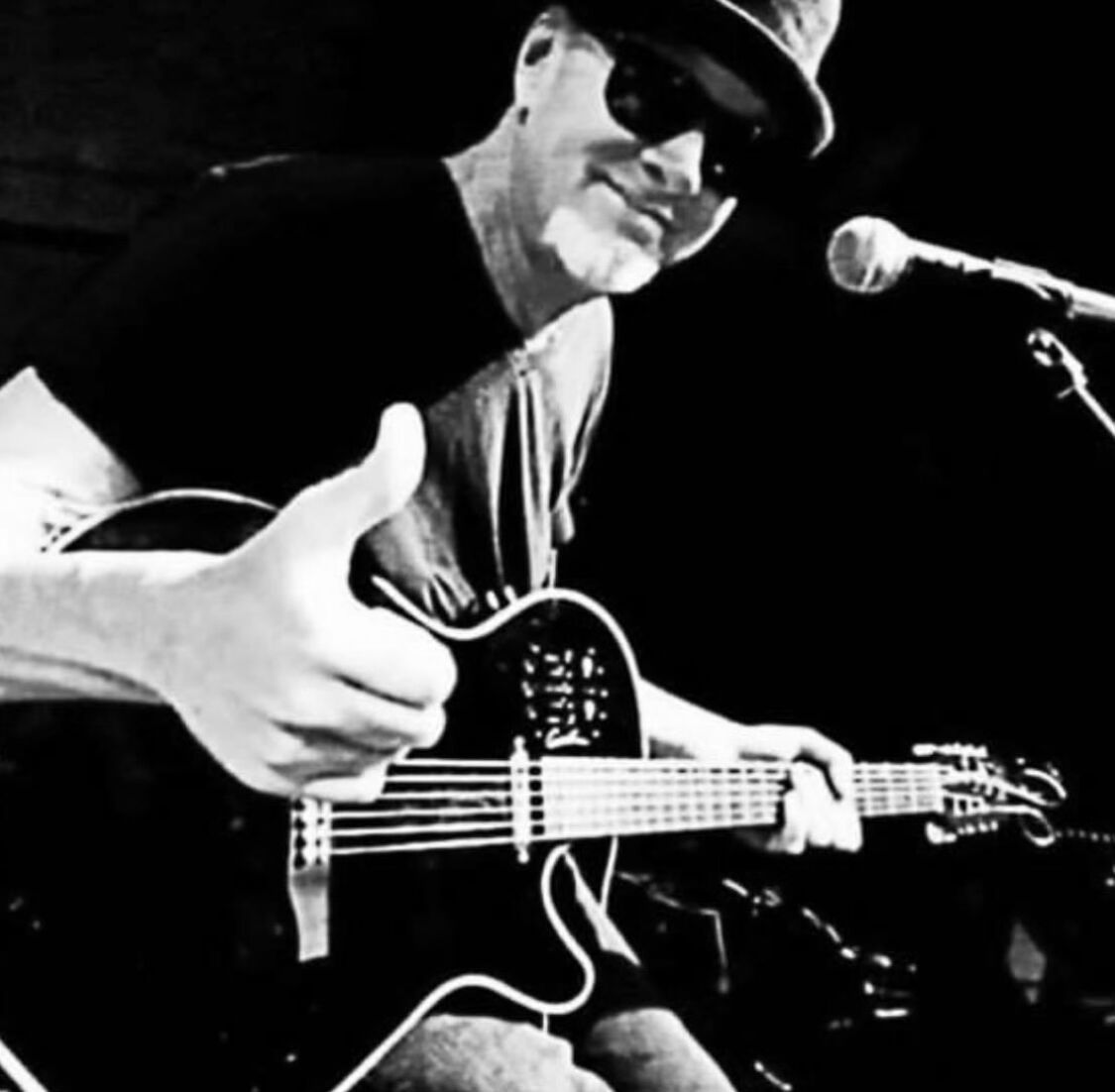 Mark Kendall performing on stage with a black-and-white hat and sunglasses look