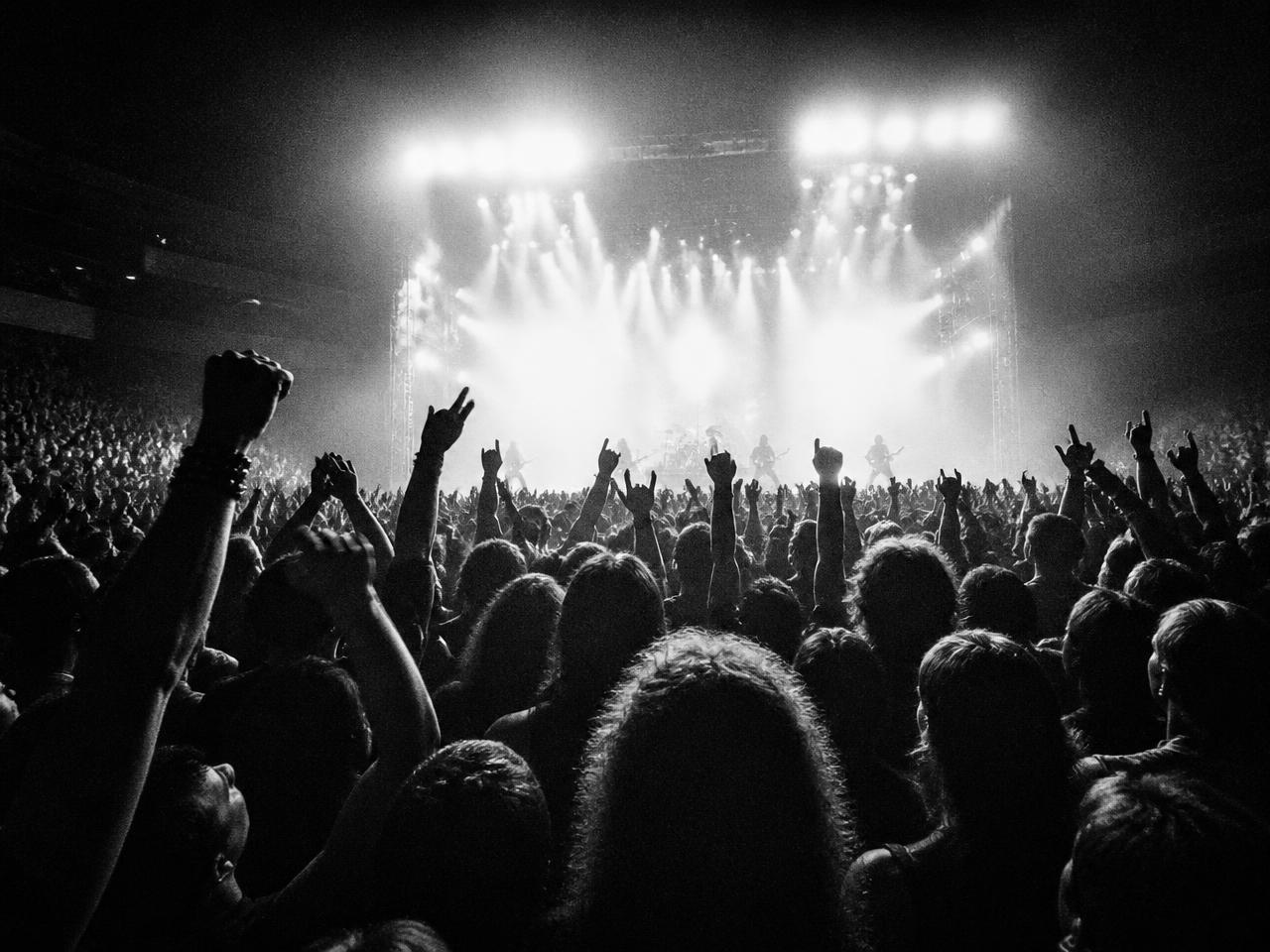 Packed rock crowd with hands raised toward the stage